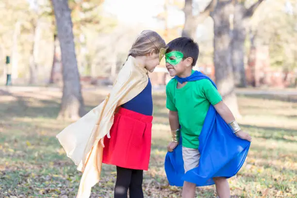 Elementary age boy and girl pretend to be superhero and villain.