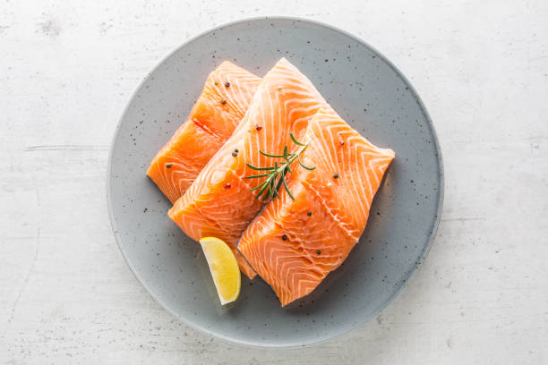 istock Salmon. Raw salmon steaks herb peper lemon on white concrete background 888647496
