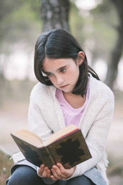 istock Adorable schoolgirl reading a book. 888660284