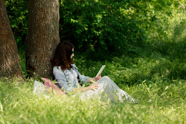 istock Summer time. Young woman at a picnic reading an e-book. 888660968