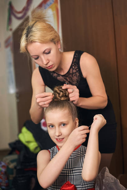 istock Mom makes daughter hairstyle preparing her for the performance. 888666146