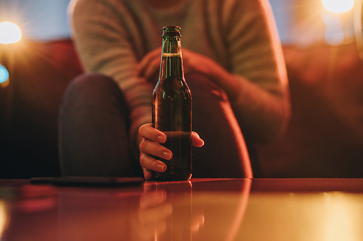 Unrecognizable person holding beer bottle on the table. Copy space.
