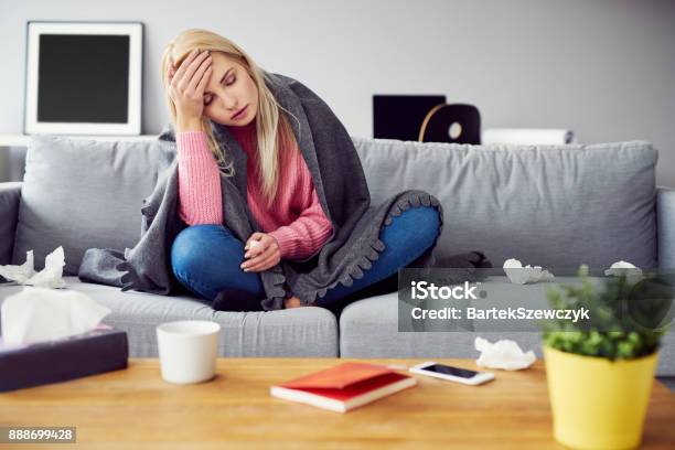 Sick Woman With Headache Sitting Under The Blanket In Living Room Stock Photo - Download Image Now