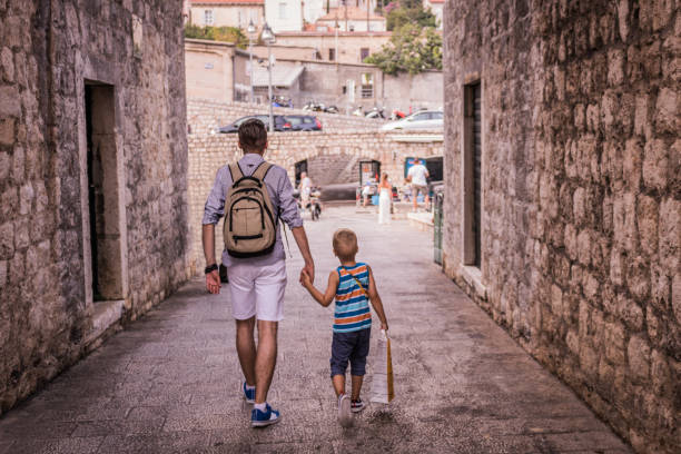 istock Father and son walking through the city and holding hands. 888717500