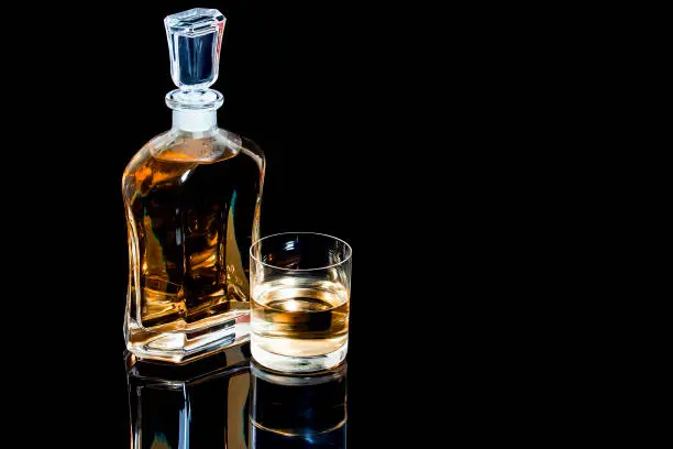 Decanter and a glass of whiskey on a black background