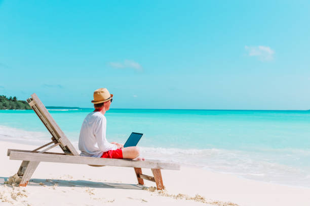 istock young man working on laptop at beach 888729218