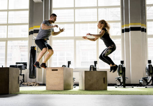 istock Man and woman jumping on boxes in gym. 888732636