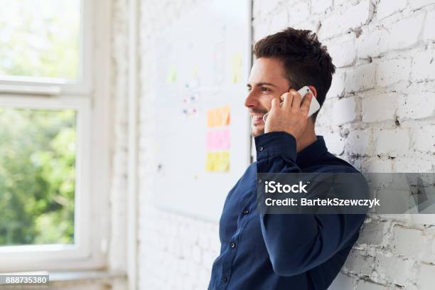 Happy Young Man Talking On The Phone At Modern Office Stock Photo - Download Image Now