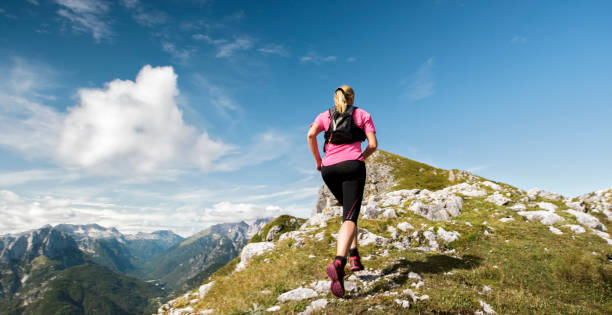 istock Female runner running up high mountain ridge in sunshine 888739302