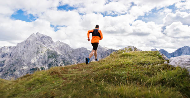 istock Male runner running up mountain ridge in high mountain range 888739346