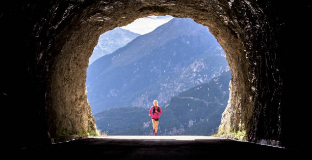 istock Female athlete running through tunnel high in mountains 888739442
