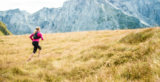 istock Female runner crossing meadow high in mountains 888739504