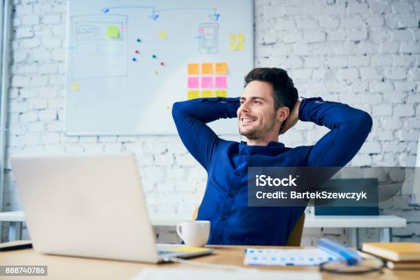 Hombre Joven Satisfecho En La Oficina Mirando Lejos Foto de stock y más banco de imágenes de Relajación