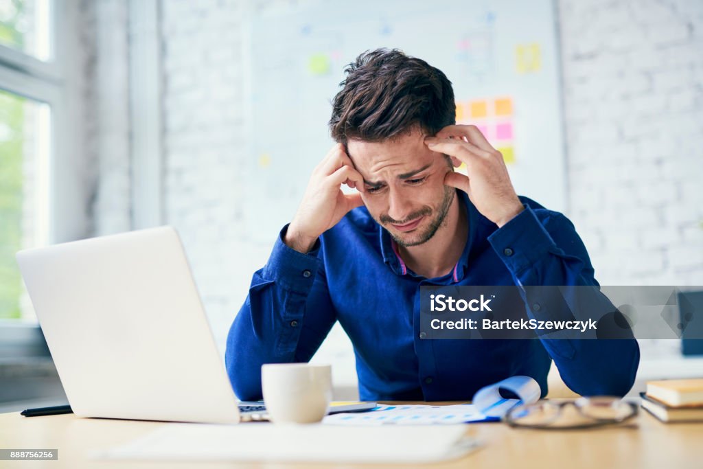 Stressed man in office looking on documents Men Stock Photo