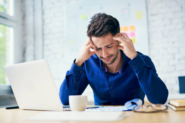 stressed man in office looking on documents - frustration computer confusion businessman imagens e fotografias de stock