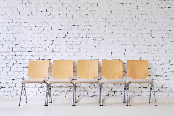 Row of five empty modern chairs in front of stylish brick wall