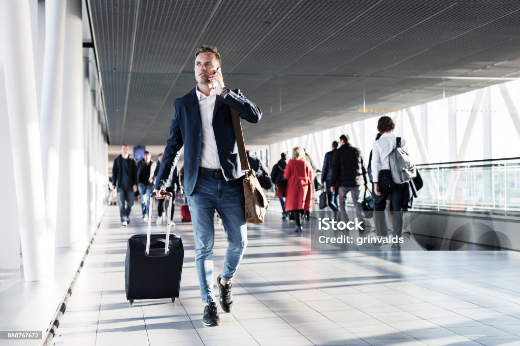 Homem ocupado falando no telefone e andando no aeroporto - Foto de stock de Aeroporto royalty-free