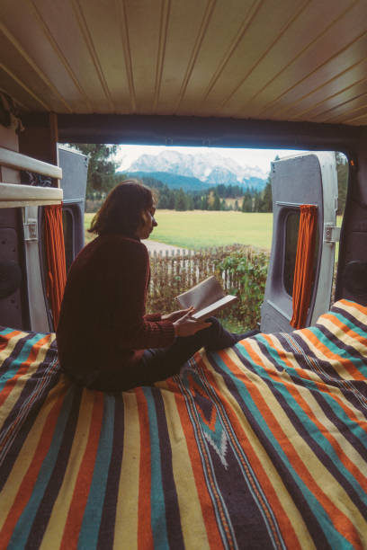 istock Woman reading book  in camper van with view on Alps 888779056