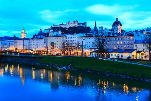 Evening twilight view of historic city of Salzburg with illuminated Cathedral and Hohensalzburg Festung across Salzach river in Austria