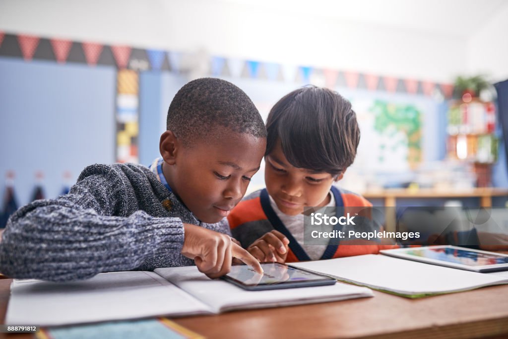 Together we will figure it out Cropped shot of elementary school children using a tablet in class Technology Stock Photo