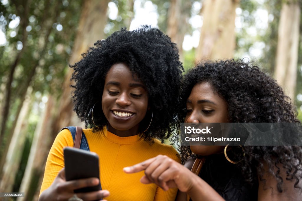 Afro descent girls using smartphone in the park People collection Nigeria Stock Photo