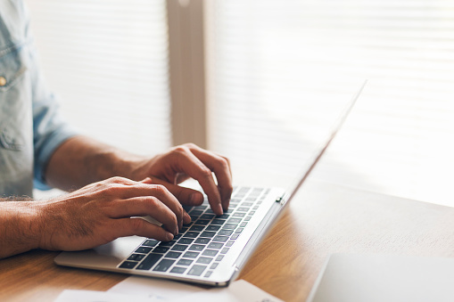 Male hands typing on laptop, close up