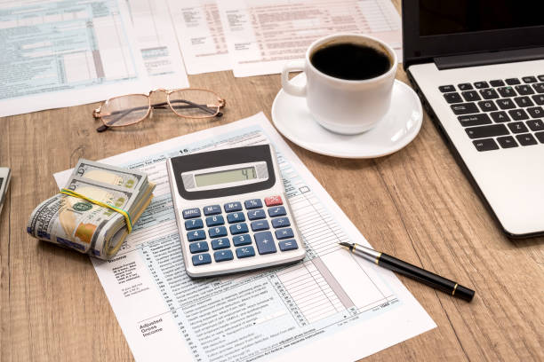 istock tax form, laptop, coffee and dollar on desk 888845952