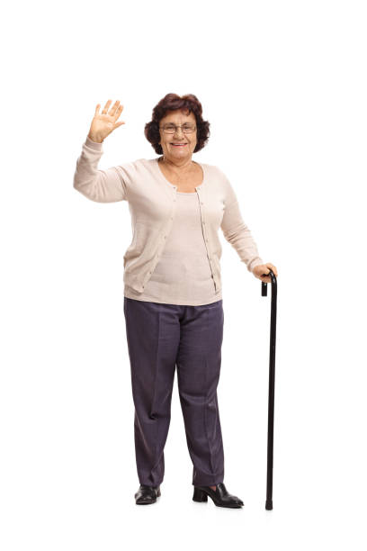 istock Elderly woman with a cane waving 888846388