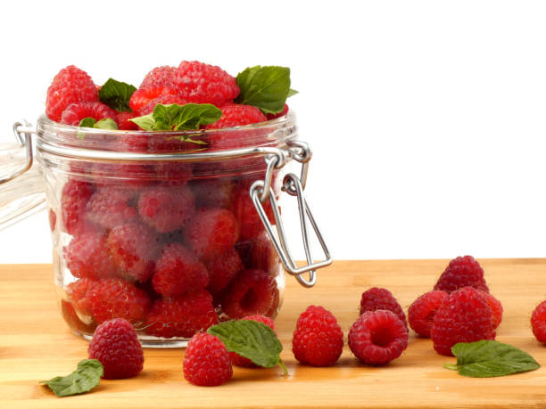 istock Jar full with raspberries isolated on wooden plank 888846718
