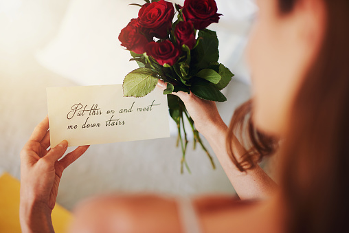 Shot of a young woman reading a note attached to a surprise gift at home