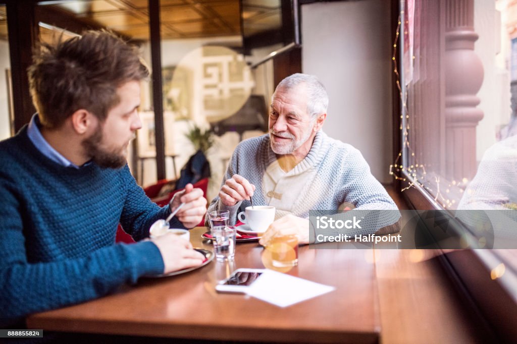 Senior father and his young son in a cafe. Senior father and his young son drinking coffee in a cafe. Senior Adult Stock Photo