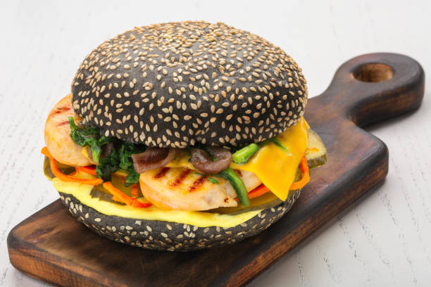 istock Black burger with fish, cheese, pickle, carrot, spinach sprinkled with sesame seeds 888856248