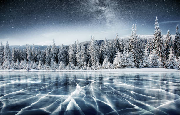 Blue ice and cracks on the surface of the ice. Frozen lake in winter mountains. It is snowing. The hills of pines. Winter. Carpathian Ukraine Europe Blue ice and cracks on the surface of the ice. Frozen lake in winter mountains. It is snowing. The hills of pines. Winter. Carpathian Ukraine Europe. winter sunrise mountain snow stock pictures, royalty-free photos & images