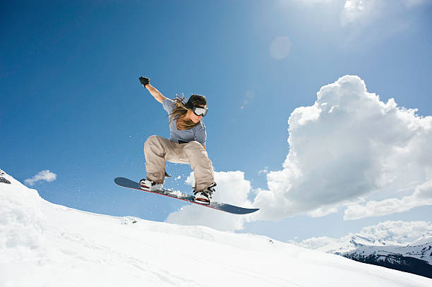 female snowboarder jumping through air - snowboardfahren stock-fotos und bilder