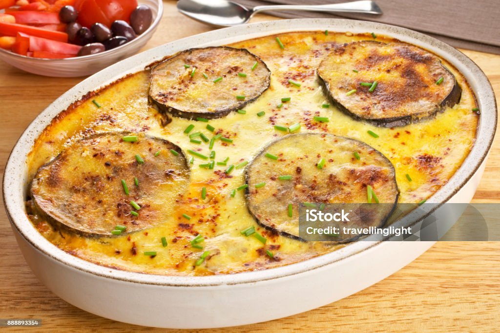 Greek Dish Moussaka Greek Dish Moussaka - a dish of Moussaka, favourite Greek meal, tasty lamb mince in a sauce with olive oil, garlic, tomato, onion and cinnamon, layered with aubergine and potato, and topped with cheesy, eggy, bechamel sauce. Typical of the Mediterranean diet. Baked Stock Photo