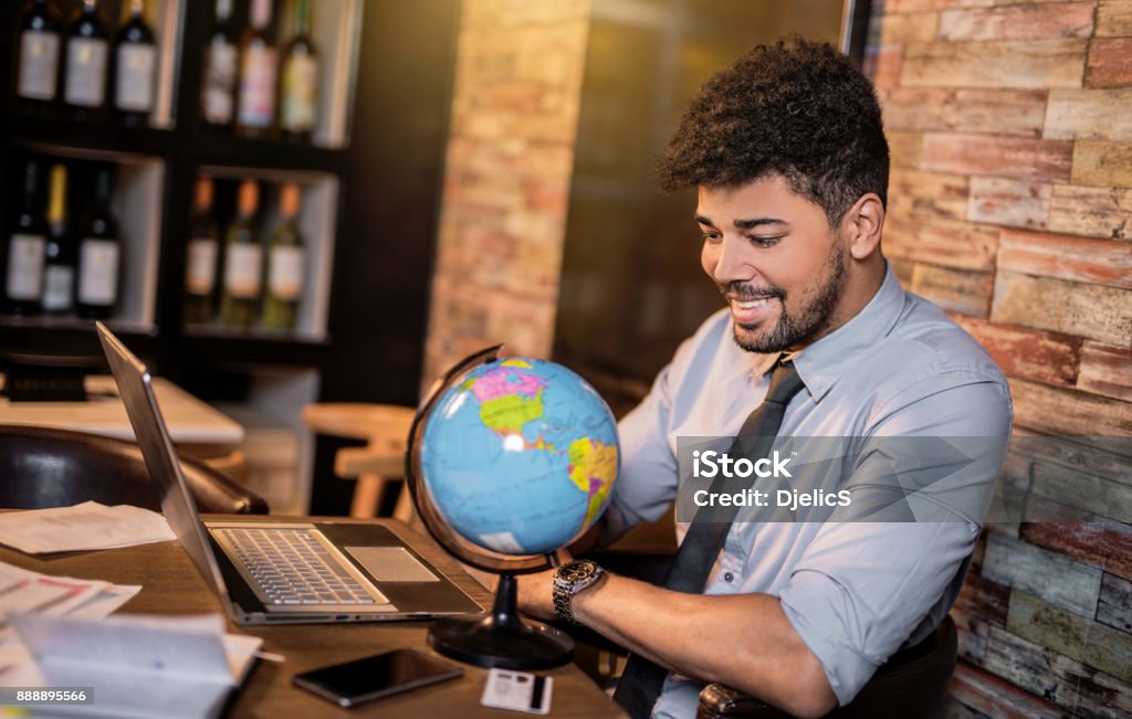 Happy African American businessman planning to travel Globe - Navigational Equipment Stock Photo