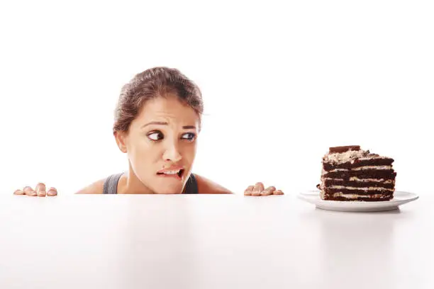 Studio shot of an attractive young woman being tempted by something sweet