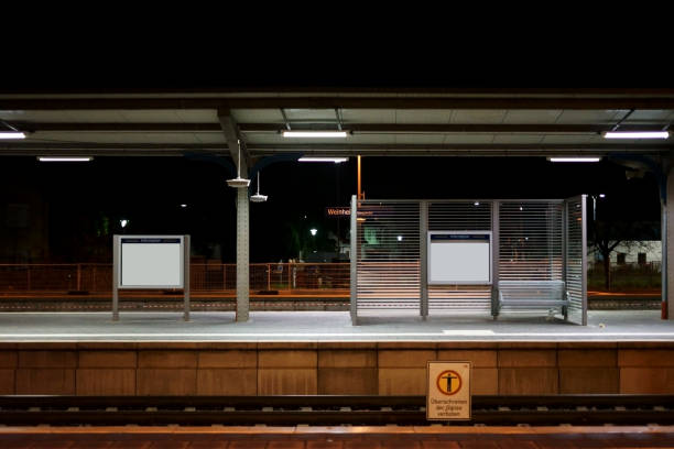 The platform of the Weinheim train station at night with seatings on a glass partition wall.