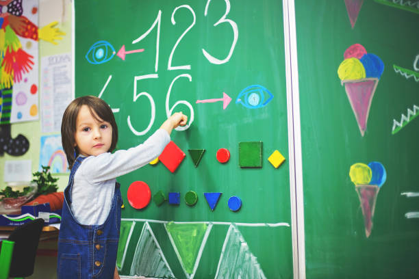 istock First grade boy at school, showing numbers and calculating 888941428