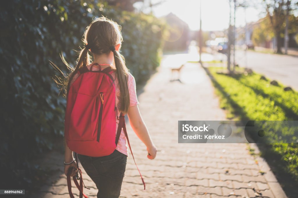 Girl walking to school Girls wearing red backpack walking to school Child Stock Photo