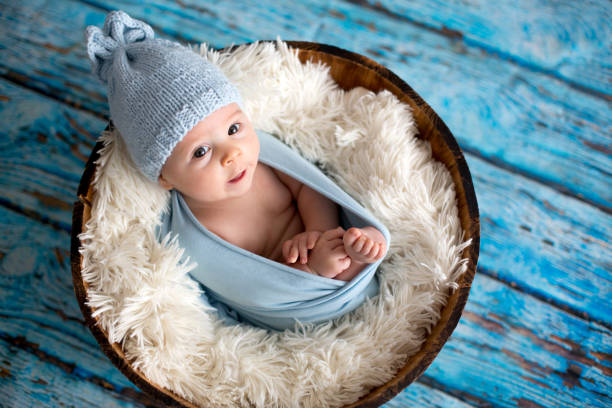 istock Little baby boy with knitted hat in a basket, happily smiling 888954162