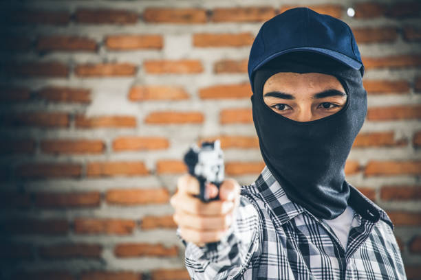 istock Robber holding a gun. Low key photo and selective focus. criminality concept. 888960324