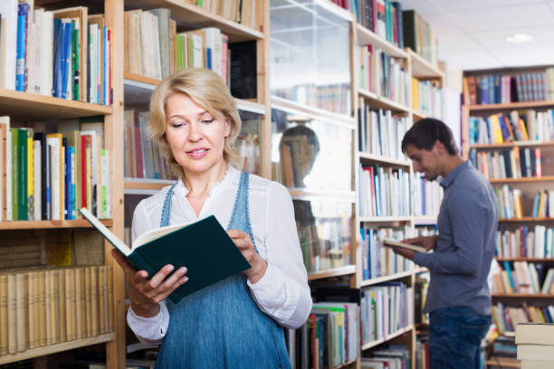 istock Cheerful mature woman looking at open book 888961374