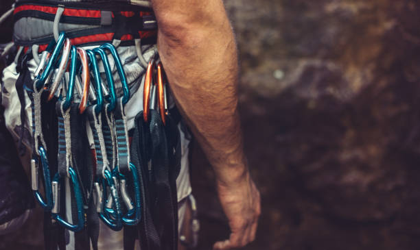 Man standing with climbing equipment outdoor, rear view. Face is not visible Unrecognizable man climbers check out climbing equipment outdoors carbine stock pictures, royalty-free photos & images