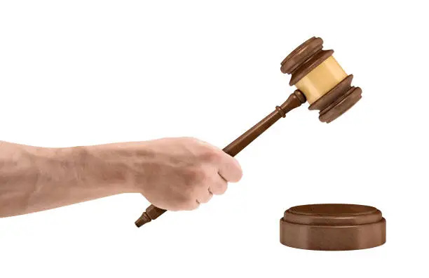 Photo of A large male hand holds a wooden judge gavel above a round sound block isolated on a white background