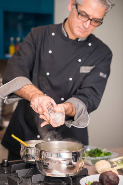 istock Professional chef preparing meal in private house: Adding salt 888983138