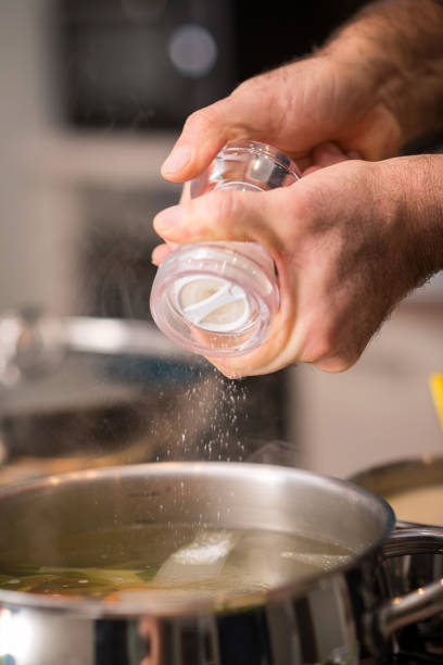 個人の家で食事を準備するプロのシェフ: 塩を加えること - 塩をふる ストックフォトと画像