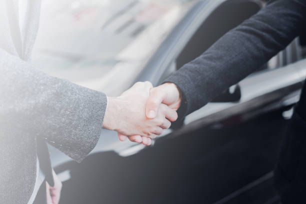 istock Businessmen shaking hands beside the car 888983504