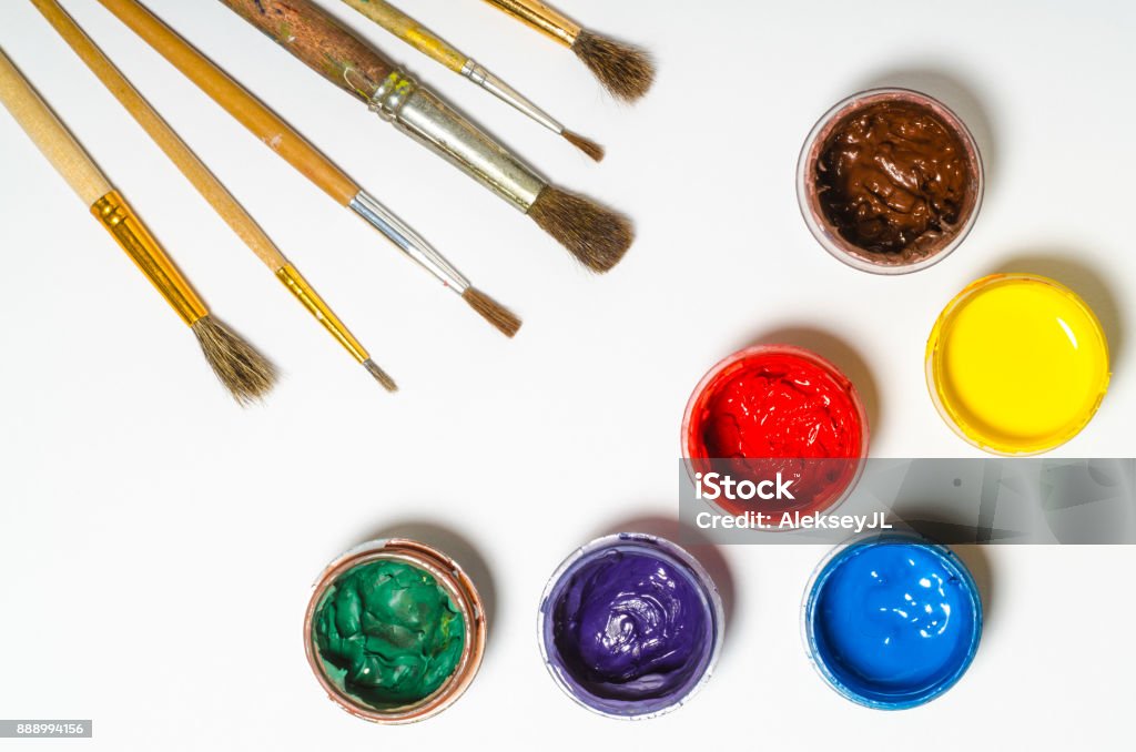 paints in jars and a brush on a white sheet of paper, top view Horizontal Stock Photo