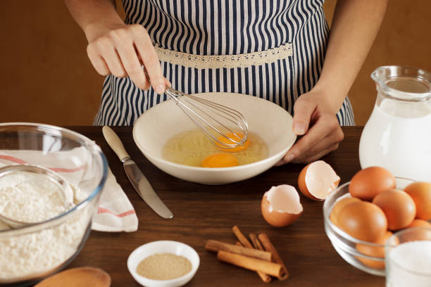 istock Woman mixing eggs in ceramic bowl for dough on wooden table. 889015642